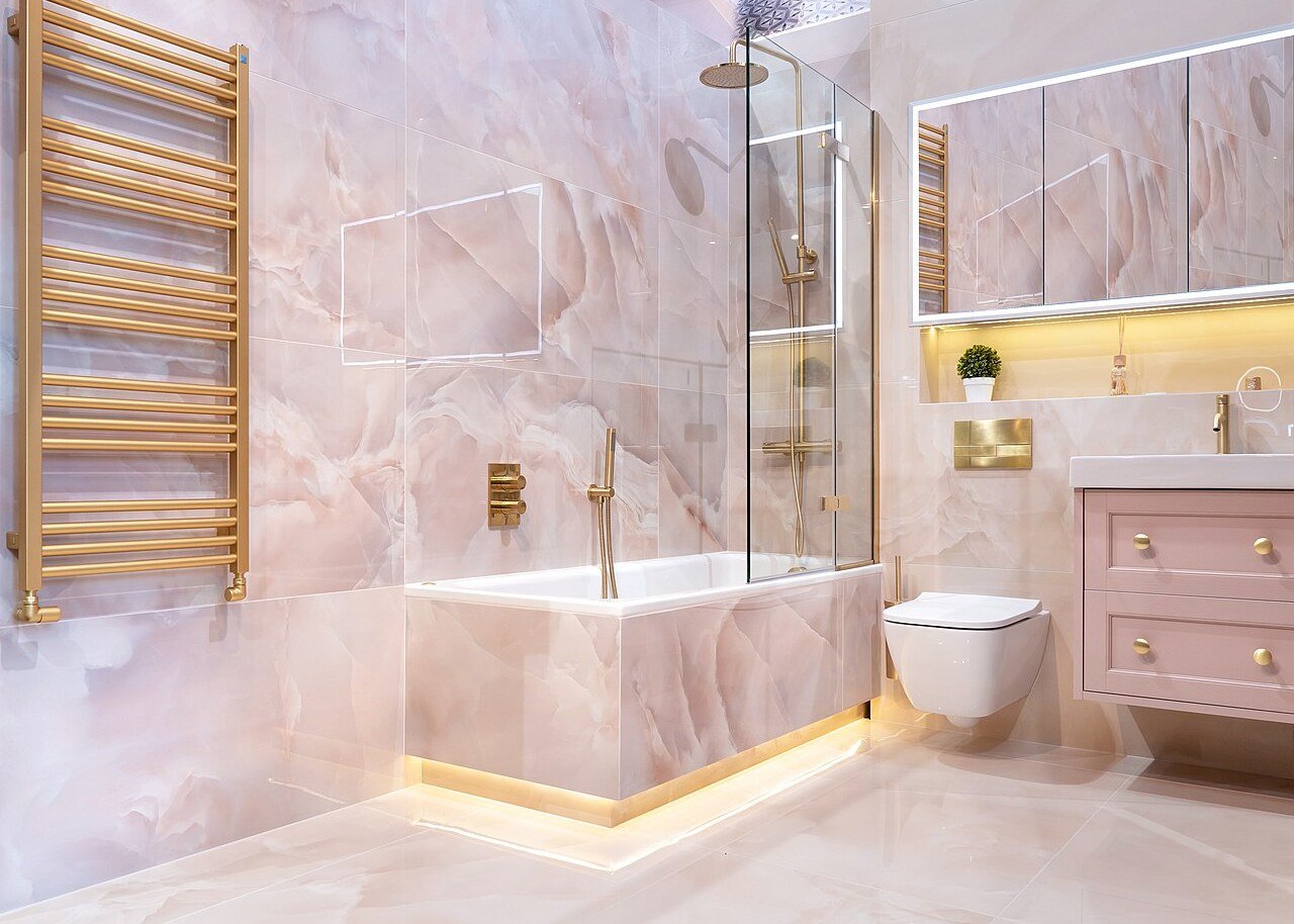 Bathroom with marble look stone tiles, a glass shower screen and gold fixtures.