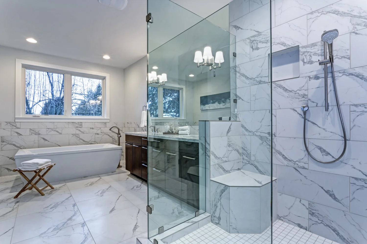 Marble-tiled bathroom with glass shower enclosure, freestanding bathtub and vanity