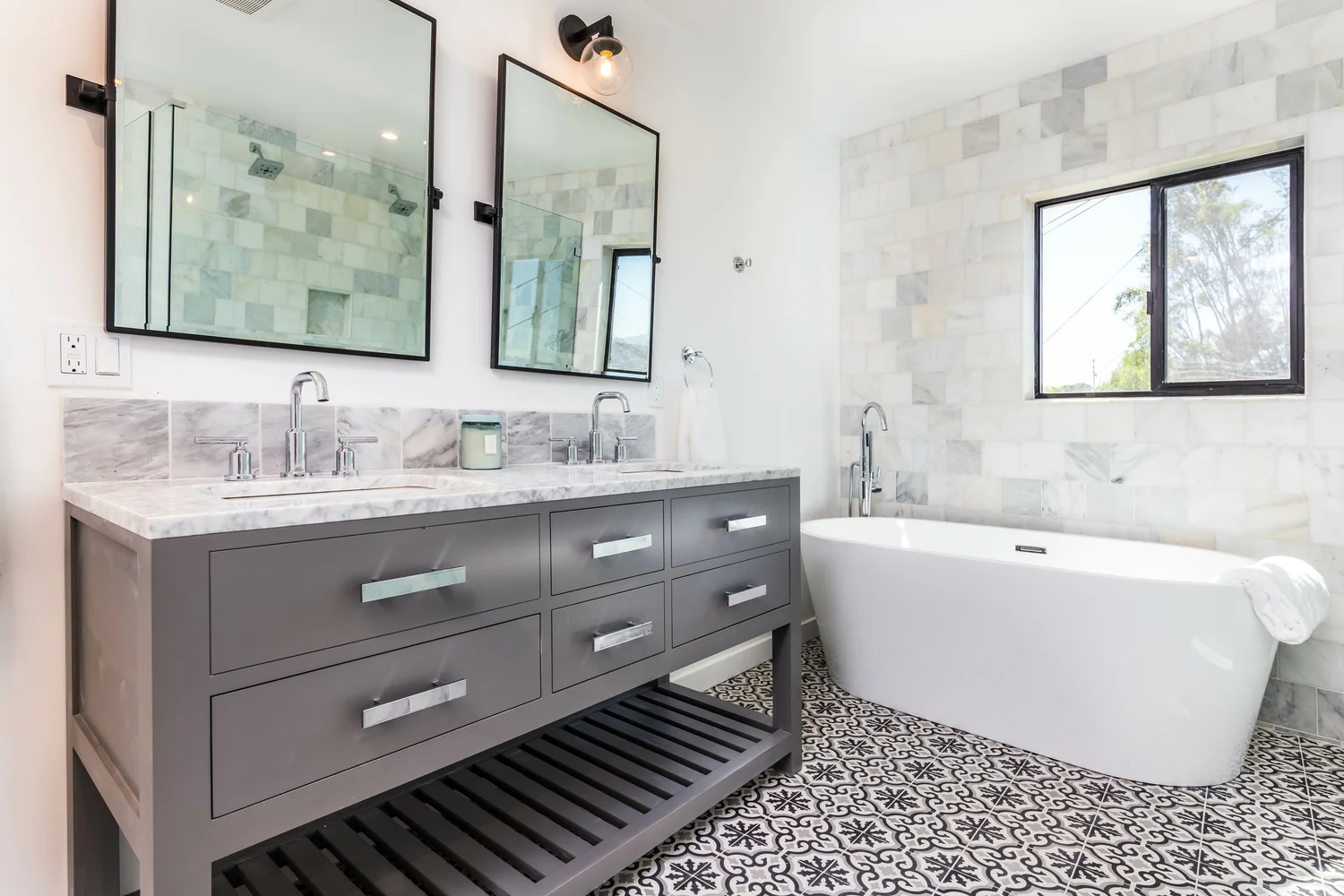 Renovated bathroom with double vanity, marble tiles and freestanding bathtub