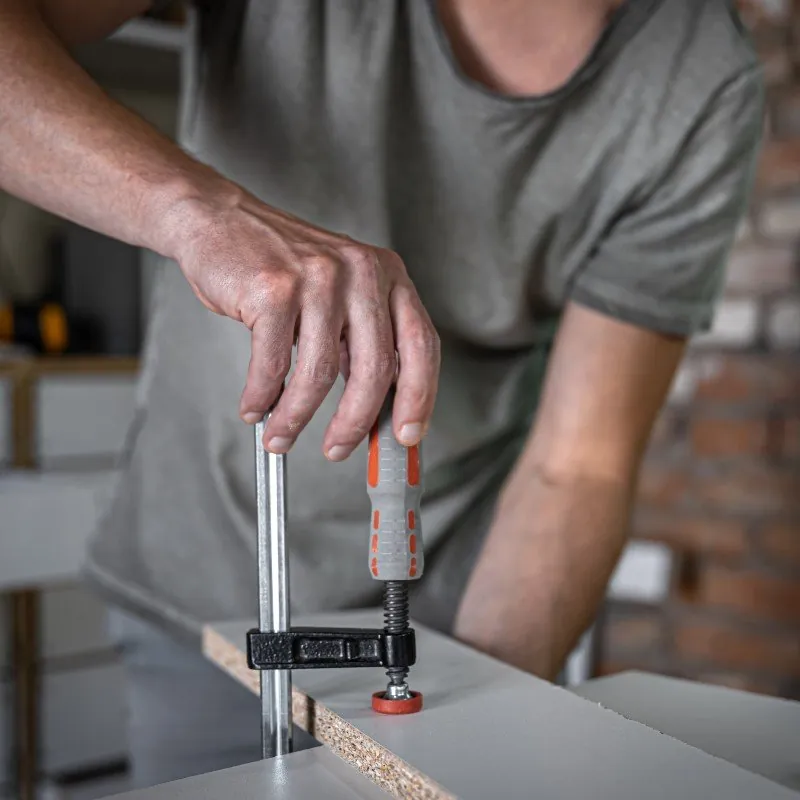 Carpenter clamping a wood board during carpentry work