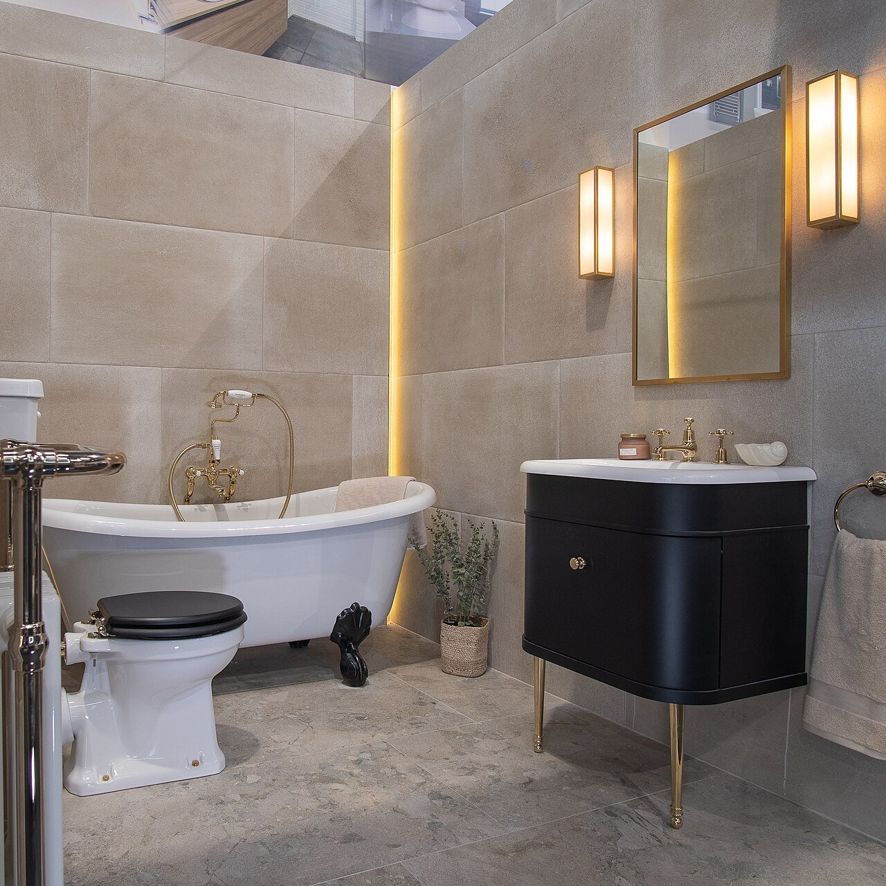 Bathroom with large stone look tiles on the walls, a freestanding tub and a dark vanity.